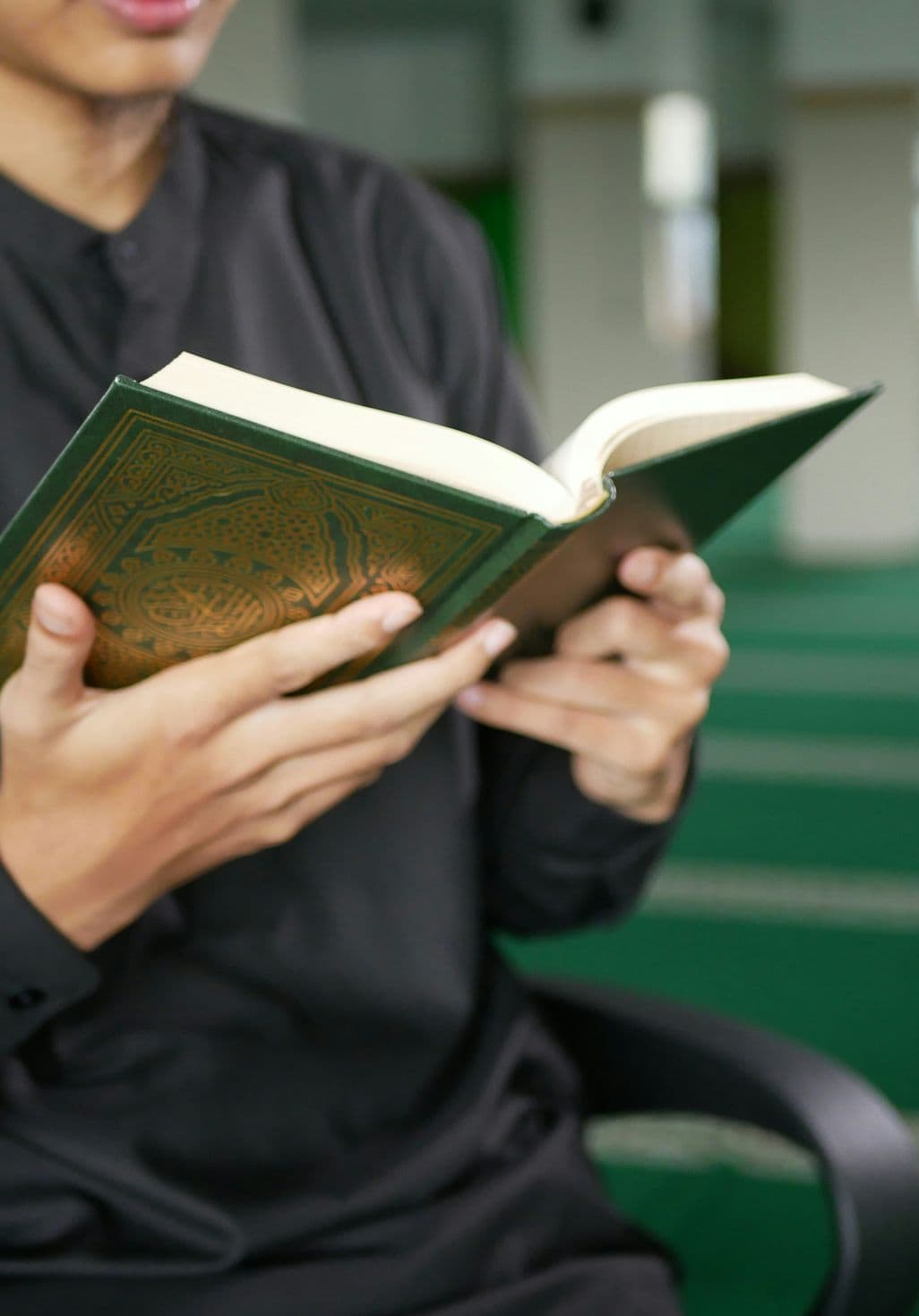 A young man reading the Quran inside a mosque